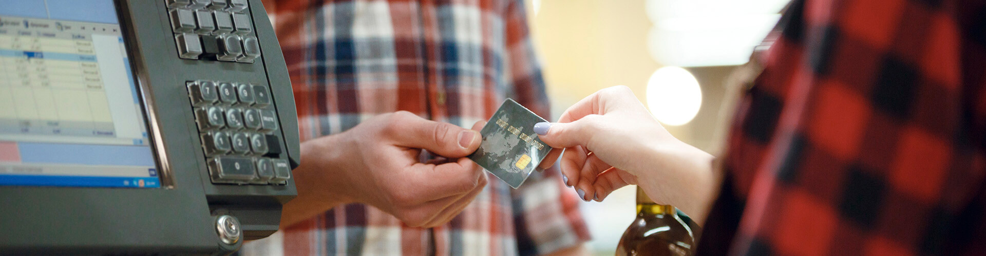 TPV Fijo - Hombre dando una tarjeta de credito a una cajera en un supermercado junto a un tpv