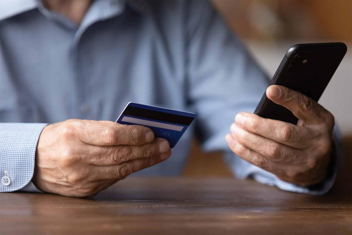 Hombre sujetando el movil y una tarjeta de crédito