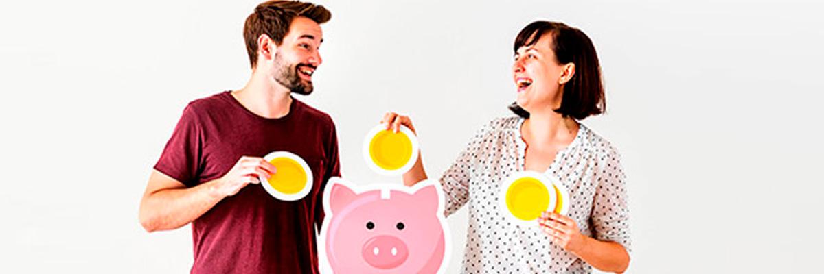 Simulador de Aportaciones Periódicas - Pareja sonriendo mientras que están metiendo monedas en una hucha con forma de cerdo Simulador de Aportaciones Periódicas - Pareja sonriendo mientras que están metiendo monedas en una hucha con forma de cerdo