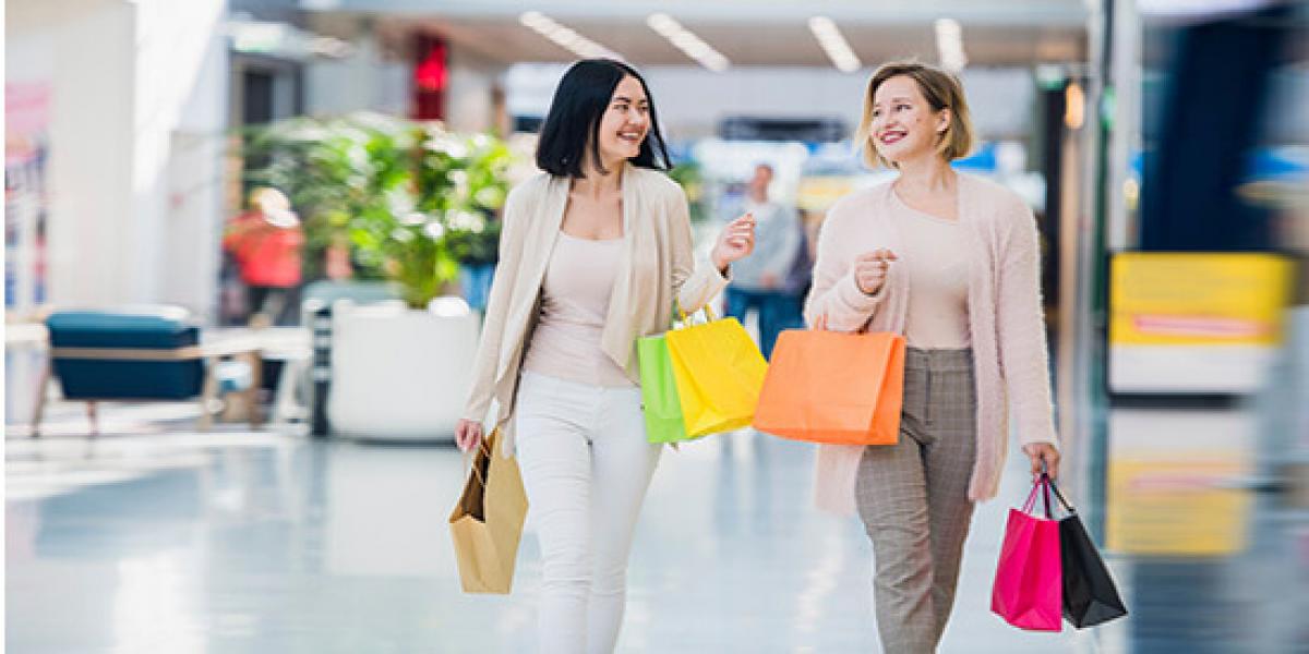 Promoción Tax Back Shopping - Dos mujeres hablando y sonriendo mientras estan de compras con bolsas en las manos en un centro comercial